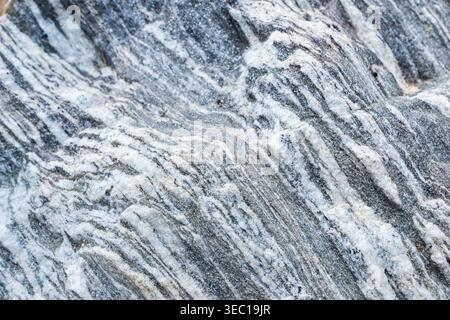 Natural textured rock stone surface with wavy layered pattern forming an abstract background. gray and white mineral layer creates fascinating and cal Stock Photo