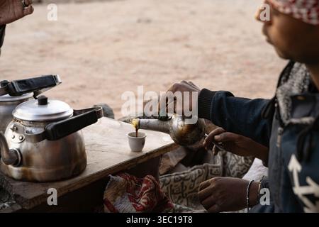 Marsa alam, egypt 21 april 2026: bedouin hands pouring hot traditional coffee from a kettle into a small cup, celebrating desert culture in marsa alam Stock Photo