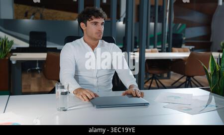 Thoughtful Caucasian business man with closed laptop thinking solving problem at table in company pensive puzzled businessman male guy boss think Stock Photo