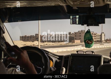 Marsa alam, egypt 21 april 2026: driver's perspective from car interior on road trip, passing unfinished resort buildings under construction in the de Stock Photo