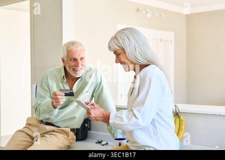 Senior couple engaged in online shopping and digital banking, utilizing a credit card for secure transactions and financial management. Stock Photo