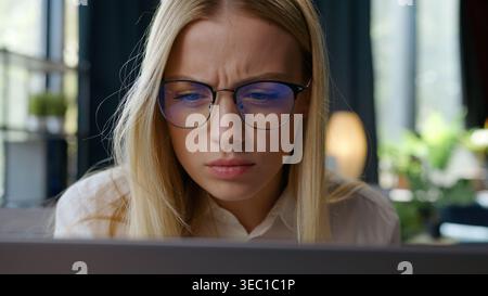 Puzzled Caucasian business woman in eyeglasses trying see blurry monitor service website take off glasses looking in computer office businesswoman Stock Photo