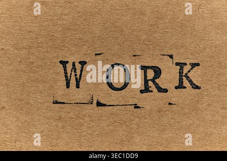 Bold black stamped text WORK on an aged, grainy paper background with typewriter aesthetic Stock Photo