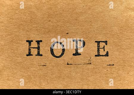 Minimalist HOPE text in black ink on grainy, sepia toned vintage paper with subtle ink splatters Stock Photo