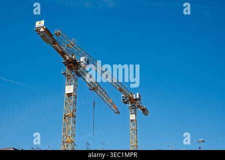 Zurich, Switzerland, April 23, 2026. Editorial view of two yellow Landolt + Co. AG tower cranes against a clear blue sky at a major urban construction Stock Photo