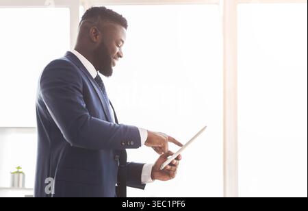 Young cheerful entrepreneur using digital tablet for business Stock Photo