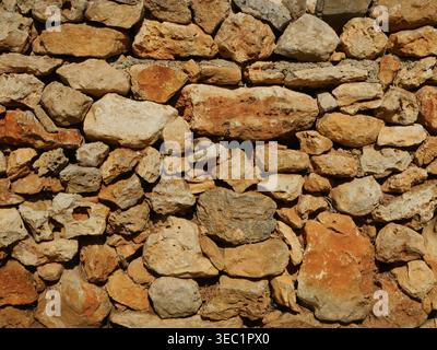 Dry stone wall made of mares natural stone in Mallorca. Detailed texture with warm tones and natural light. Stock Photo