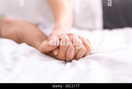 Holding Hands in a Cozy Moment on Soft Bed Sheets During a Quiet Day Stock Photo