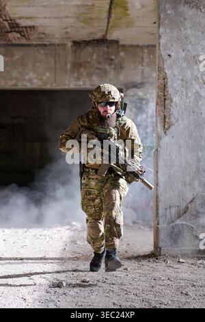 Armed Soldier in Tactical Gear Running Through Abandoned Building During Urban Military Training Stock Photo