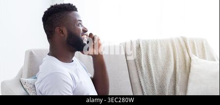 Smiling Man Enjoying a Phone Conversation at Home in Natural Light Stock Photo