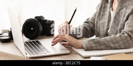 Female journalist working with laptop and camera Stock Photo