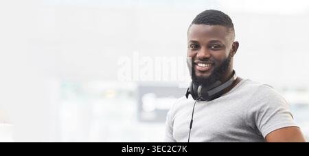 Smiling Man With Headphones Enjoys Music While Relaxing in a Modern Urban Space Stock Photo