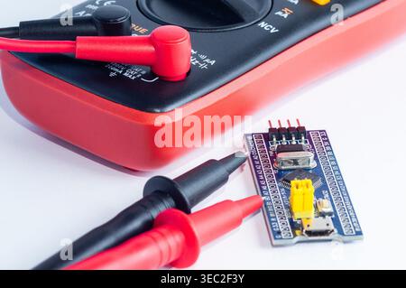 Multimeter with measurement probes and electronics board on a white background Stock Photo