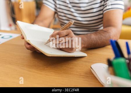 Young Indian man writing academic notes at desk Stock Photo