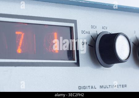 Close-up view of a classic digital multimeter with illuminated orange display showing the reading 7.81. The black rotary dial is set to DCV position. Stock Photo