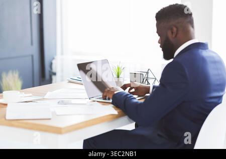 Back view of young businessman working with laptop in office Stock Photo