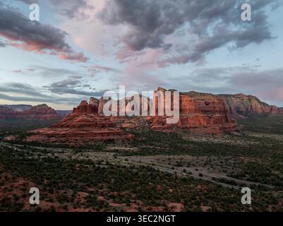 Aerial view of Bell Rock and Courthouse Butte in Sedona Arizona at dusk with dramatic clouds and highway crossing desert valley Stock Photo