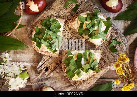 Three slices of bread with leftover Easter eggs and fresh chopped wild garlic leaves collected in spring Stock Photo