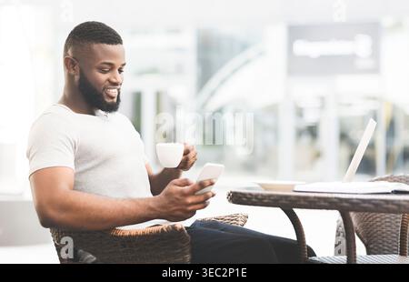 Man Enjoys Coffee While Using Smartphone in Modern Cafe Environment Stock Photo