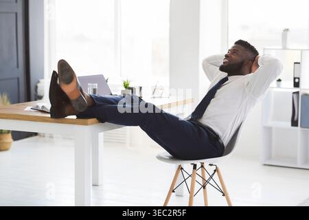 Joyful young manager relaxing on chair in white modern office Stock Photo