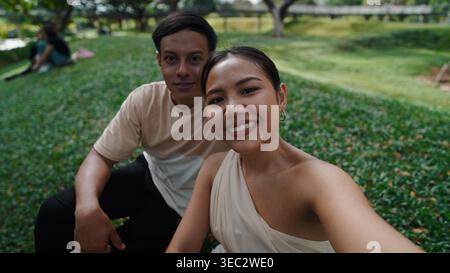 Young couple taking selfie, smiling during outdoor park leisure moment Stock Photo