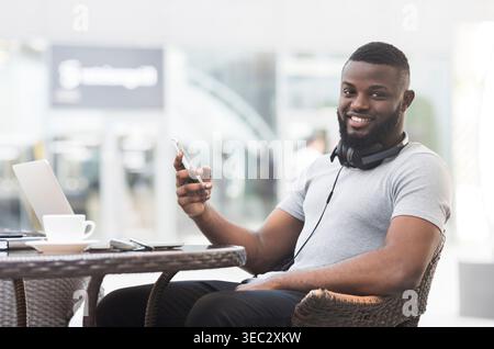 Young Man Enjoying Coffee While Using Smartphone at Outdoor Cafe Stock Photo