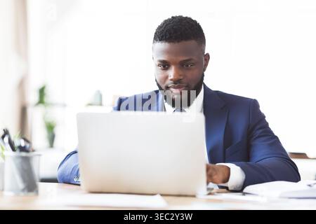Hard-working black man typing on laptop in office Stock Photo