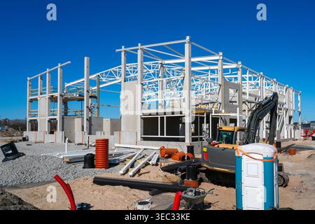 Industrial building construction site with steel frame, excavator and materials under blue sky Stock Photo