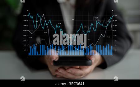 A close-up view of hands holding a smartphone with financial charts illustrating growth trends, perfect for themes around business analytics and Stock Photo