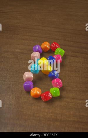 A bracelet made of colorful dice on a wooden table. Stock Photo