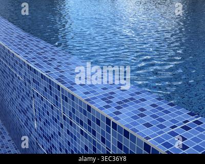 Swimming pool with blue tiles and rippling water creating a calming texture background. Mobile photo Stock Photo