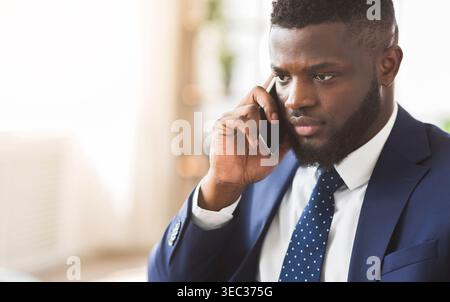 Handsome angry businessman talking by smartphone with employees Stock Photo