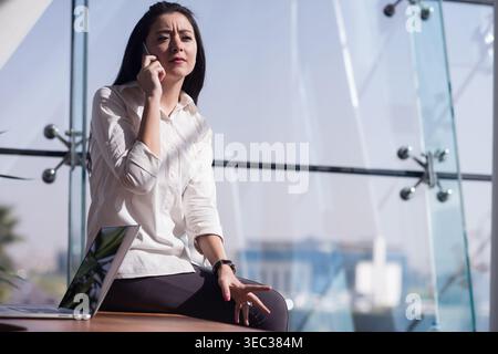 Middle Eastern businesswoman on phone in modern glass office during startup meeting and remote work Stock Photo