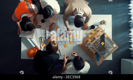 Top down view of skilled engineer team compare between blueprint and house plan. Aerial view of group of architect or designer discussing and point Stock Photo