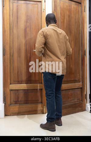 Tall paneled wooden double doors are standing centered in narrow entry alcove with brass hardware Stock Photo