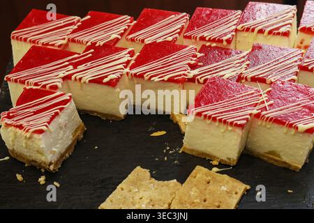 The cheesecake is cut into squares and there are crackers on the tray Stock Photo