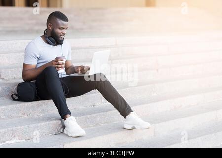 Young Man Working on Laptop While Sitting on Steps in Urban Setting During Daylight Stock Photo