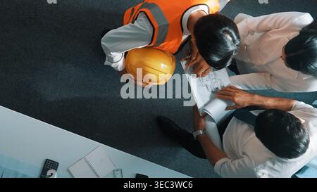 Top view of skilled architect engineer team looking at blueprint together. Aerial view of smart designer holding tablet while working together and Stock Photo