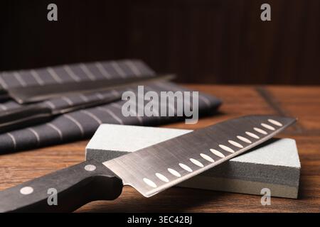 Sharpened knife and whetstone on wooden table. Space for text Stock Photo