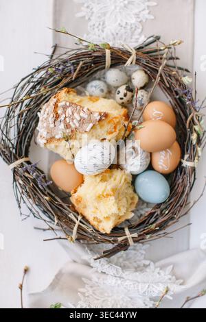 Close-up overhead view of a rustic wreath on a dining table filled with decorated Easter eggs and traditional Russian kulich Easter bread Stock Photo