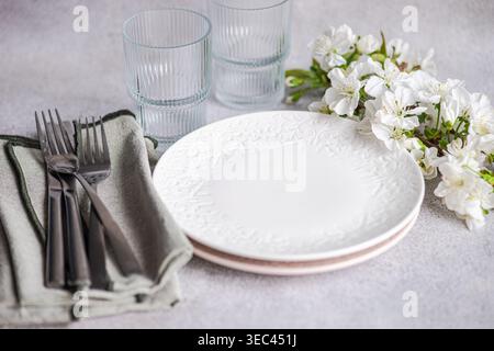 Close-up of plates, glasses, cutlery and napkins on a table with cherry blossom flowers Stock Photo