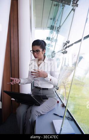 Middle Eastern businesswoman in a virtual meeting at a modern glass office space for startup collaboration Stock Photo