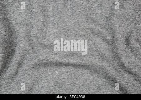 Crumpled grey melange jersey fabric texture with soft waves and shadows. Stock Photo