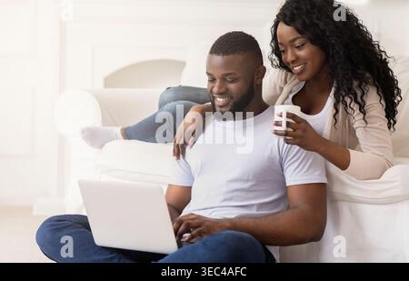 Couple Enjoying Quality Time Together While Using a Laptop at Home in the Afternoon Stock Photo