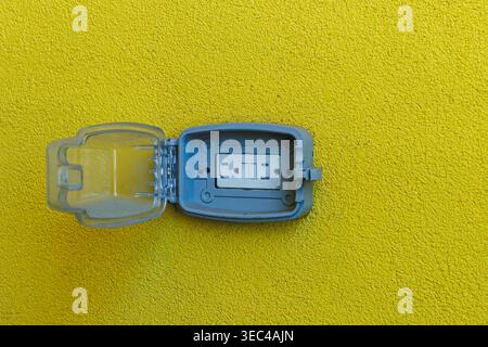 Small blue case with latch opened on yellow background showing a gray device inside for holding or storing small items Stock Photo