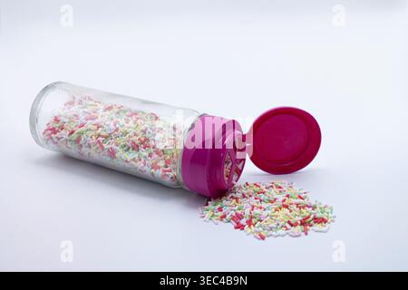 Sprinkles pouring from a vibrant pink dispenser, ready for decorating desserts Stock Photo