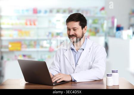 Pharmacist using laptop at table in drugstore Stock Photo