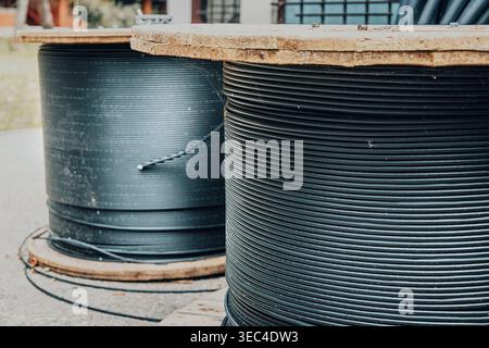 A fiber spool holding black cable beneath parked vehicle, with wooden ...