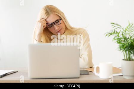 Feeling Tired And Stressed. Woman Working On Laptop Stock Photo