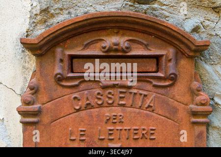 Close-up of an antique, rusty cast iron Italian mailbox embedded in a stone wall. The embossed text reads "Cassetta per le lettere" (Mailbox). High-qu Stock Photo